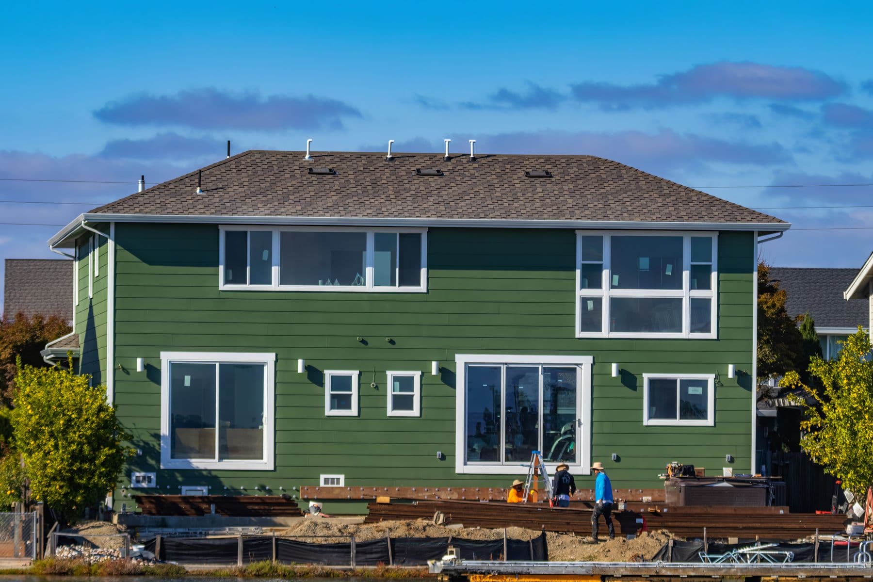 Installers fitting new fiber-cement lap siding on a two-story home exterior